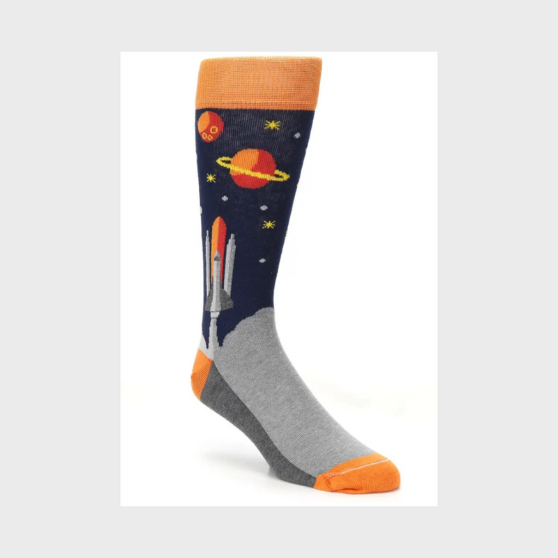 Blue Orange Spaceship Socks start on Greys and Dark Blue. The Cuffs, Heels and Toes are Orange. The Spaceship lifts off from a planet into a field of stars with planets all around.