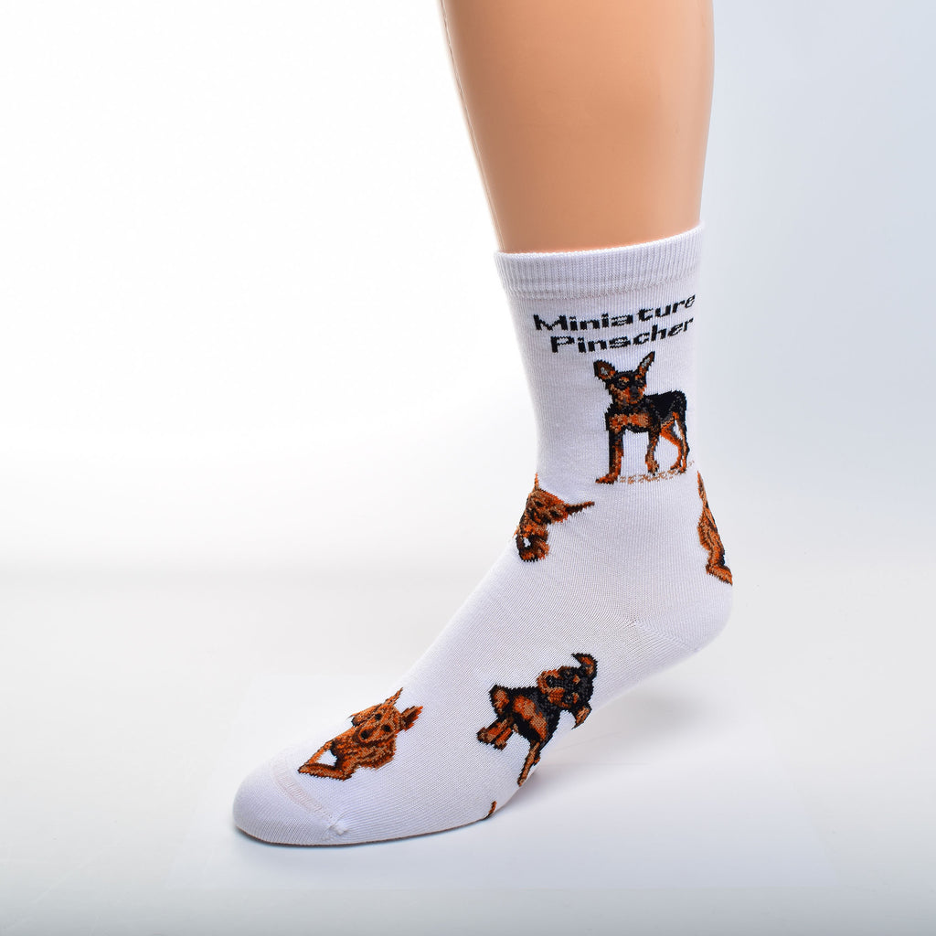 On a White background with Black bold Print reads, "Miniature Pinscher". Under this are four different poses of Laying Down, Looking out at you saying Who Me? Running after a ball maybe and one standing at the ready.