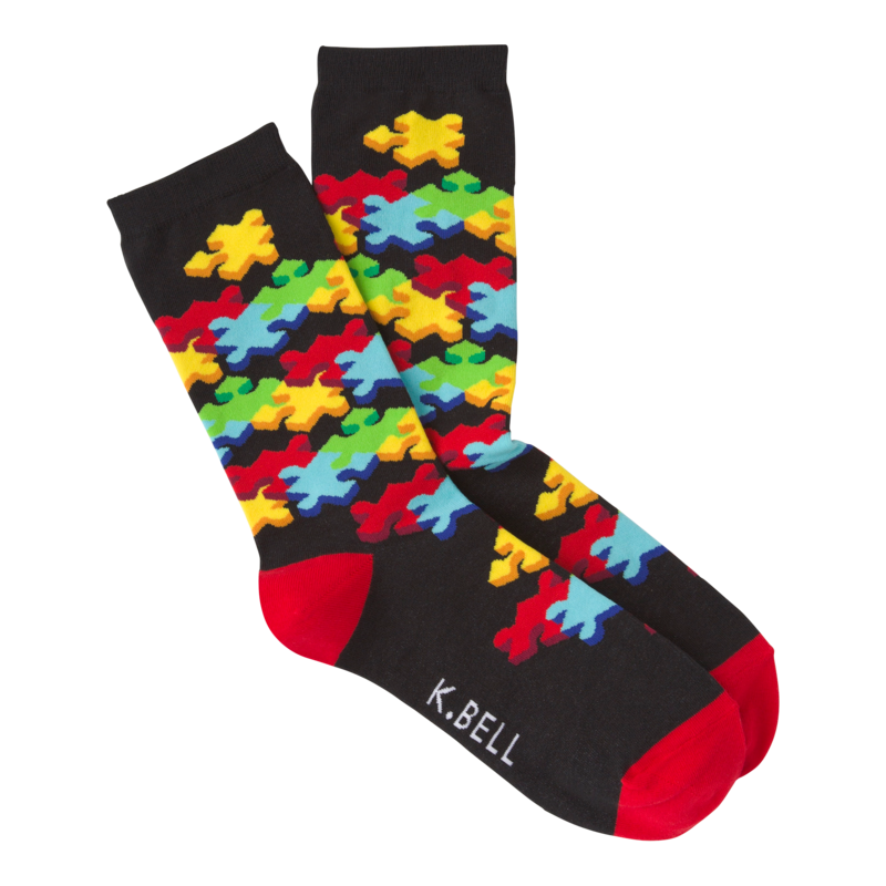K Bell 3D Womens Jigsaw Sock starts on a Black background and has Red Heels and Toes. Under the Cuff starts the Puzzle Pieces with a Bright Yellow Puzzle Piece which also takes more down the sock to the foot with Bright Colors  Red, Green and Blue.