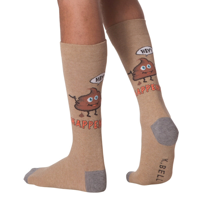 K Bell Mens It Happens Sock begins on a Brown background with Charcoal Heather Grey Heels and Toes.  Below the Cuff starts the Funny Graphic first with a word bubble saying, "HEY!" Then a BIG Turd Icon lets out a Little Turd Icon. Under Him reads in Bright Orange Bold Letters, "HAPPENS"  This is on a model.