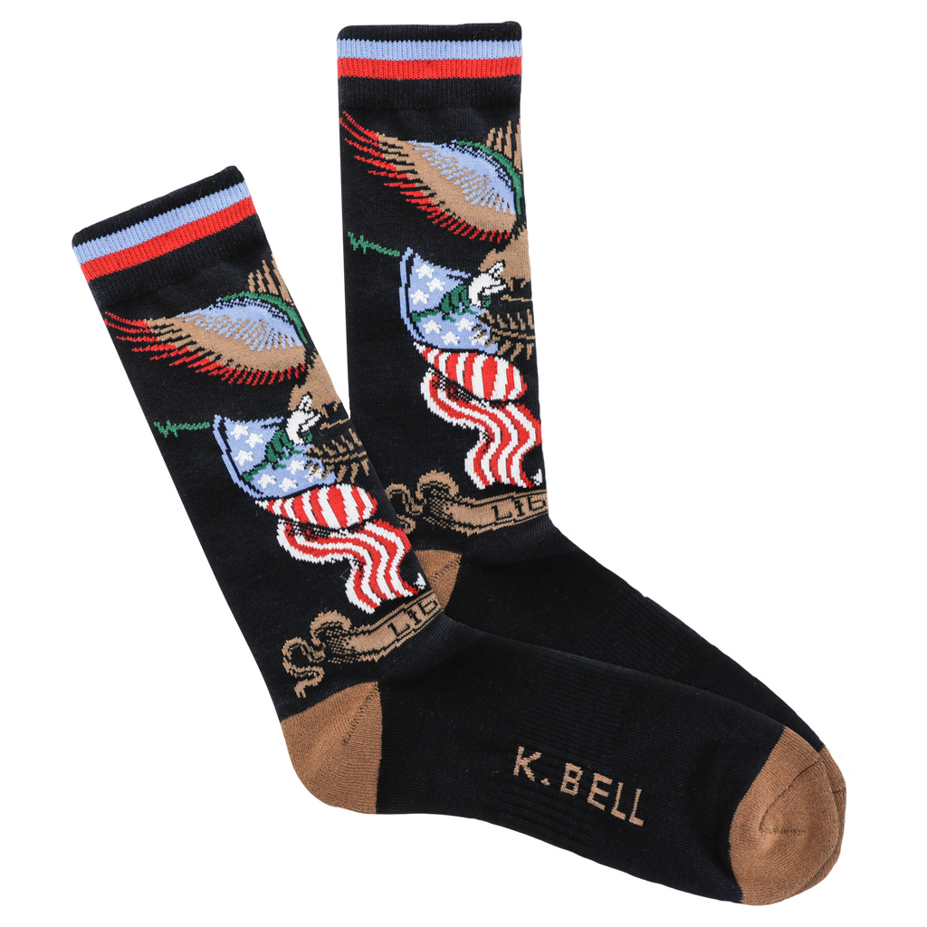 K Bell American Made Mens Tattoo Eagle Over Flag Sock begins on a Black background with Seal Brown Heels and Toes. The Eagle holds the Rod that carries the Flag Bunting. The Eagle is Chocolate, Dark Green, Red, White, Blue and Black. The Flags are Red, White and Blue. Under the Flags is Bunting in Chocolate with Liberty written on it.