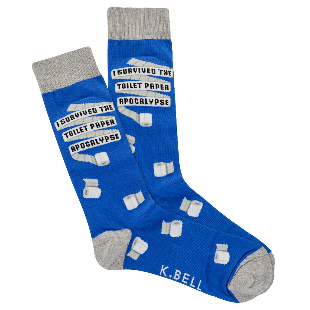 K Bell Mens Toilet Paper Sock begins on a Royal Blue background and Heathered Charcoal Grey at the Cuffs, Heels and Toes. The Toilet Paper is Unfurled for the words to be written. "I SURVIVED THE TOILET PAPER APPOCALYPSE." Toilet Paper Rolls are scattered over the Sock.
