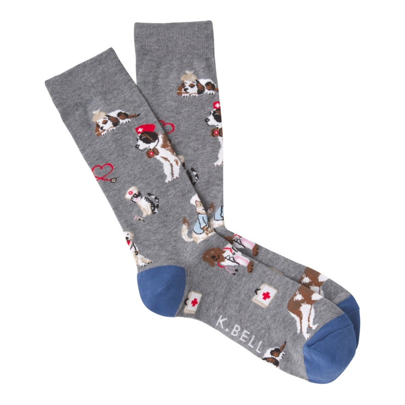 K Bell Mens Veterinarian Socks start out on a background of Charcoal Heather Grey. The Heels and Toes are Indigo Dye. Hats are Red or White with Medical Cross Signs and so are their Bags. Stethoscopes are Red and Black. Dogs and Cats are White, Brown Black and some are wearing outfits. 