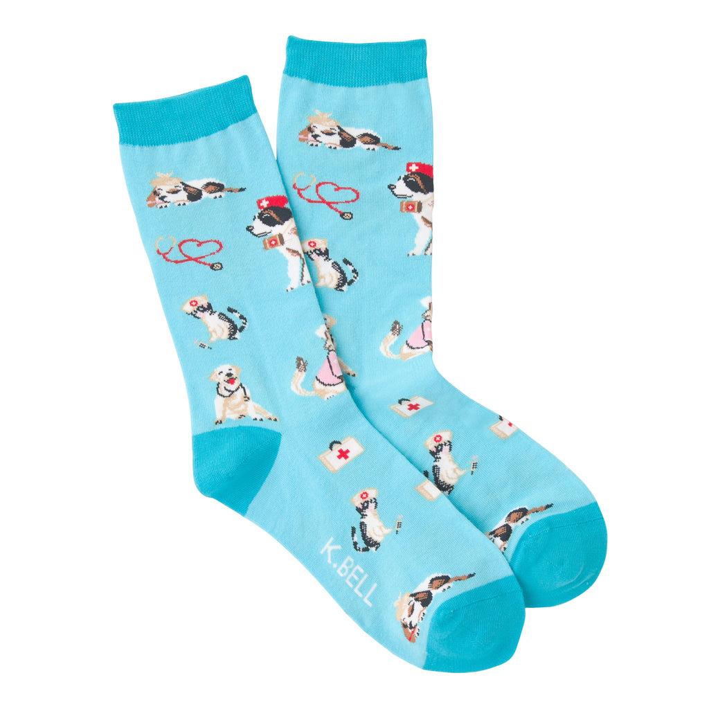 K Bell Womens Veterinarian Sock starts on a Turquoise Blue background with Teal Cuffs, Heels and Toes. All around the Sock are Dogs and Cats playing Veterinarians. At least one is playing a patient! All over you see Red  or Black Stethoscopes being used by Vets in Medical Hats.