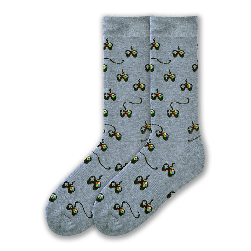 K Bell Mens Controller Sock starts on a Grey background with Controllers all over the sock. They are Black with little buttons in Red, Yellow, Blue and Green and a D pad Grey. The cord if it has one is Black.