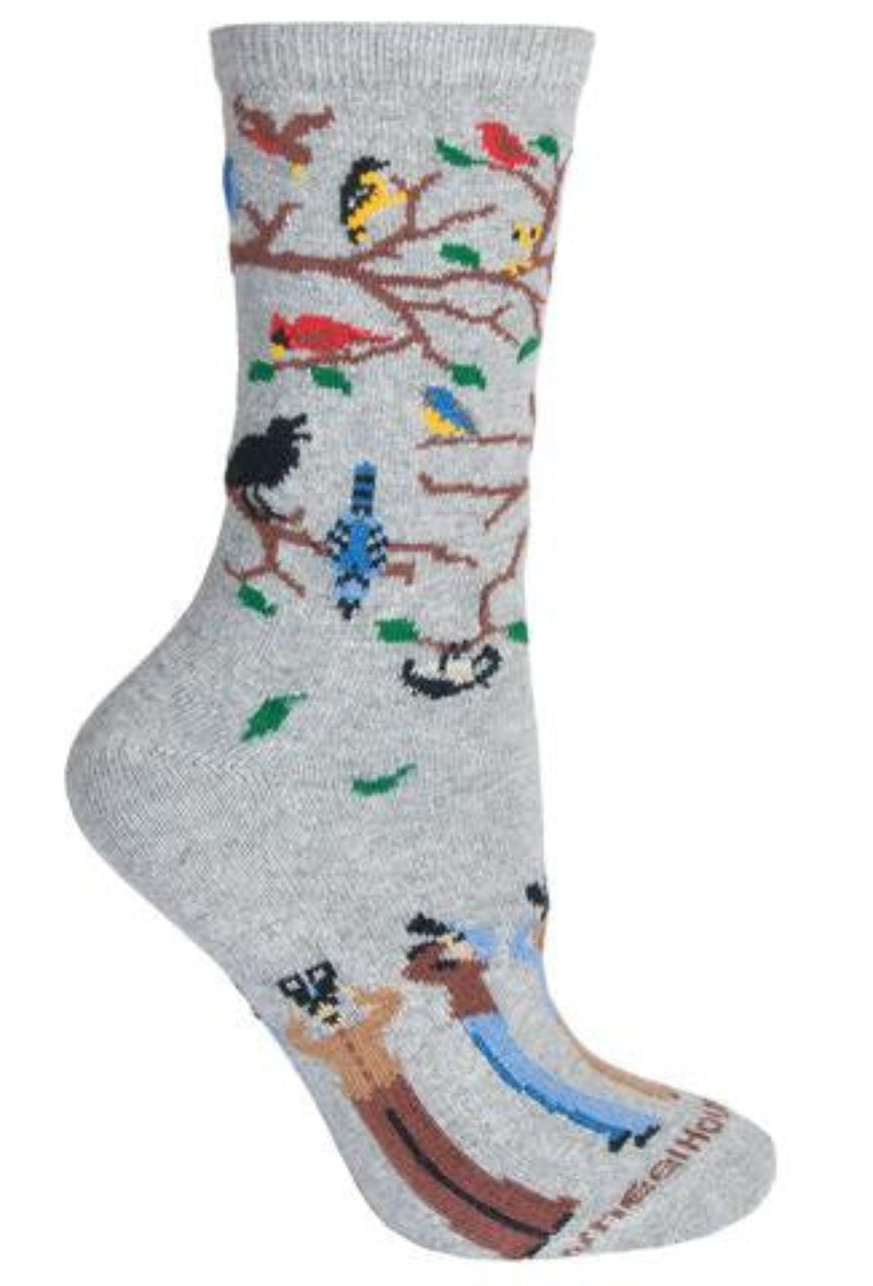 Wheel House Designs Birdwatchers on Grey Sock have Birds in a fall season tree with Green Leaves falling down. The Brown branches are bare better to see all the Birds in the Tree and in the Air. The Birds appear to be Cardinals, Goldfinch, Blue Jays, Crows and Mourning Doves. Below the Heal are Men and Women with Field Glasses watching the birds above.