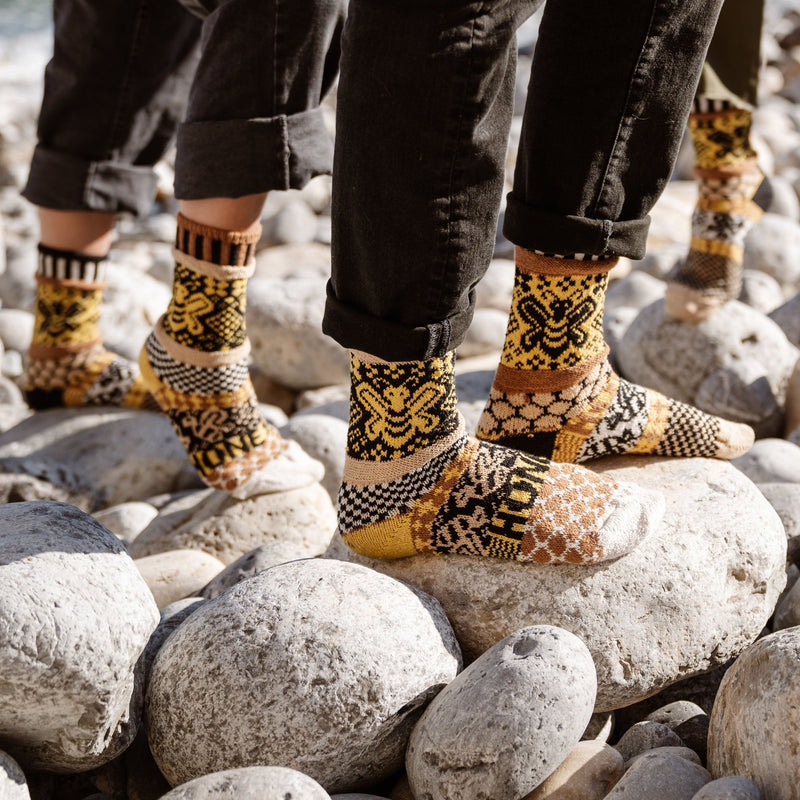 This photo shows a few models wearing the Solmate Adult Crew Honey Bee Socks from the side angle.