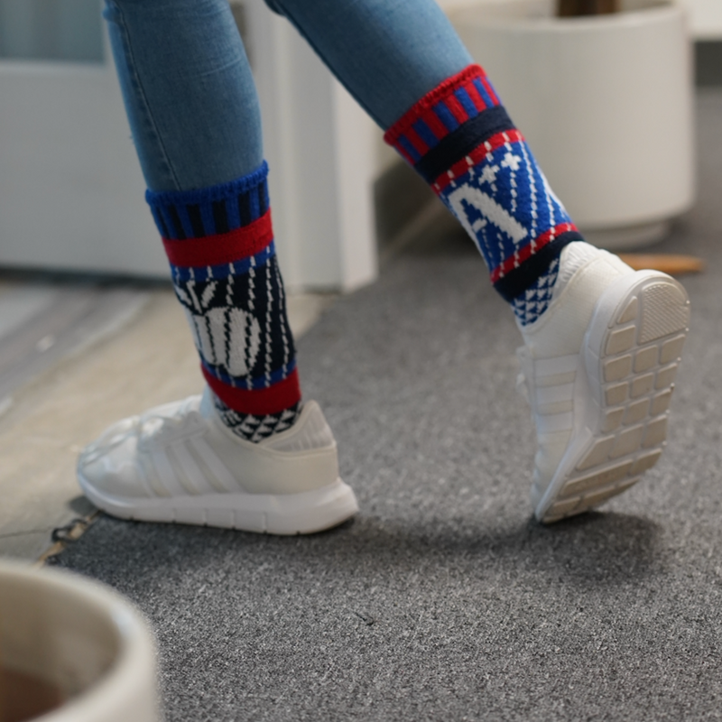 Solmate Adult Teacher Crew Sock on a Model  showing the Red, Royal Blue, Navy and White with the Apple and the A++ Graphics.