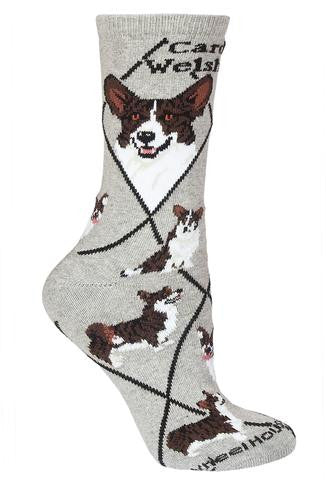 Wheel House Designs Cardigan Welsh Corgi Sock starts on a Grey background with Black Diamonds all over. It has under the Cuff in Bold Black Print Cardigan Welsh Corgi. Then in the First two Diamonds are the Profiles of a Front and Side View. Poses below are of a Show Stance, Running, Sitting, Looking Up for Approval.