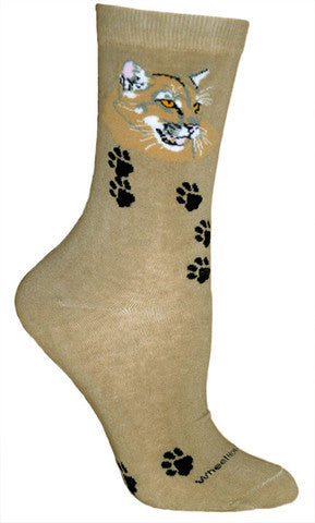 Wheel House Designs Mountain Lion Sock is on a background of Khaki. There are Black Mountain Lion Paw Prints over the sock. The Face of the Mountain Lion is at the top of the Sock in Whites, Black and Sandy Brown with Light Grey. Pink is for mouth and ears.