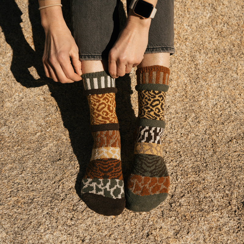 Patterned Savanna Animal Socks worn by a model on a hilltop.
