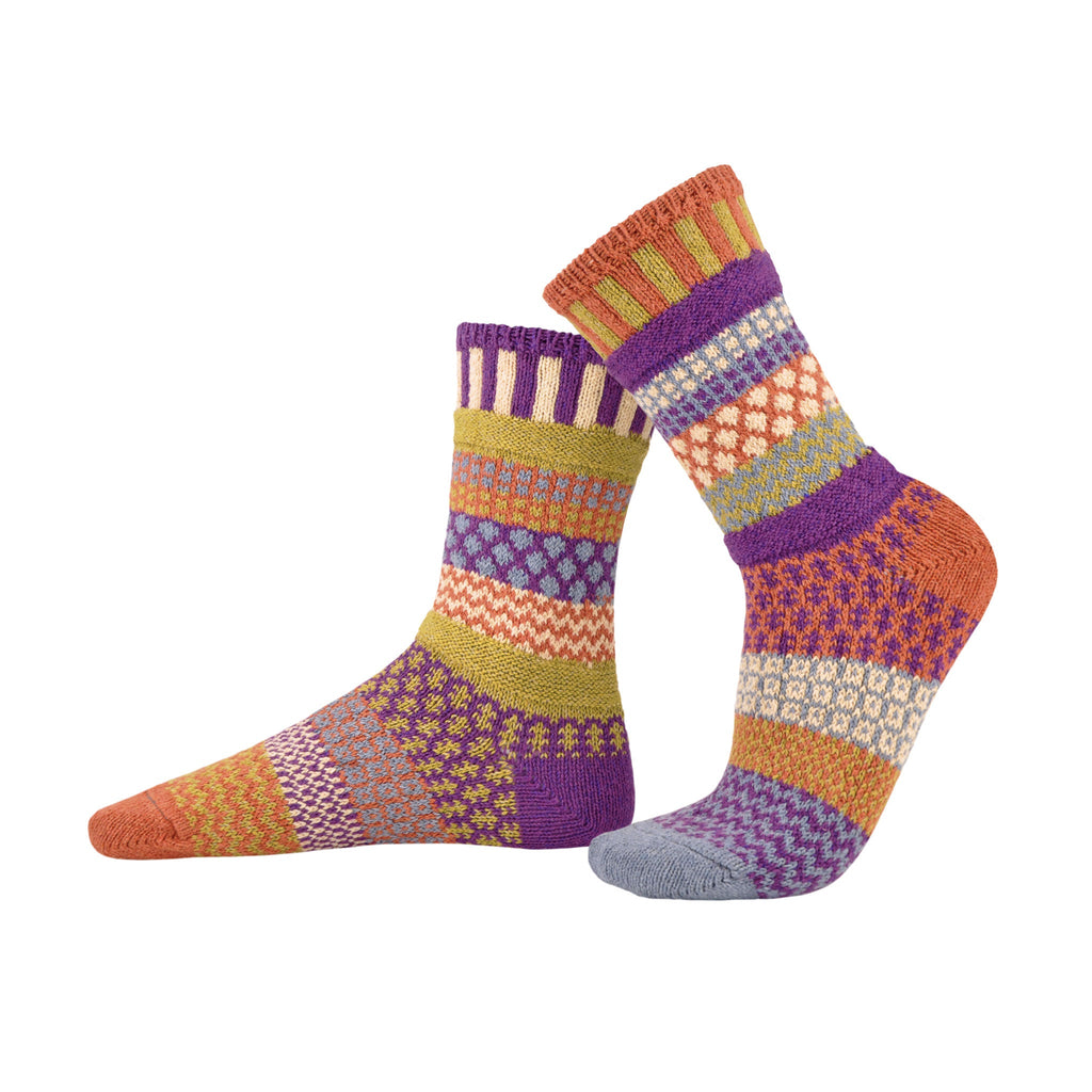 Solmate Mismatched Socks in Geometric Bright Orange, Purple and other colors on a White background.