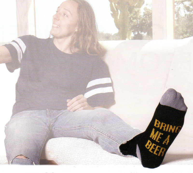 Model Wearing K Bell American Made Mens Beer Sock on a Couch with his foot up showing "Bring me A Beer".