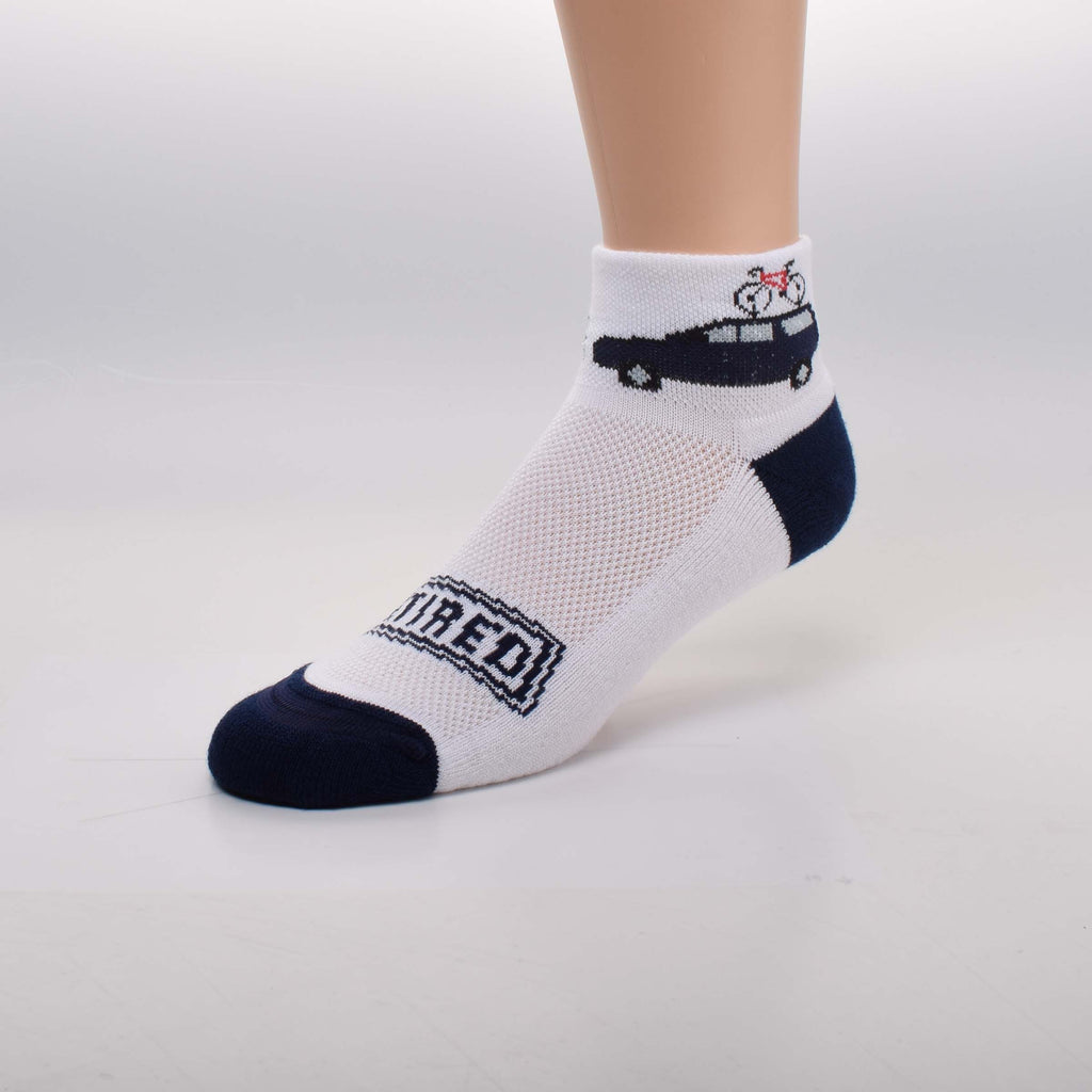 For Bare Feet Retired Travel Sock starts with the Cuff that has a Vehicle towing a Speed Boat and a Bicycle on top of the Vehicle. The Bottom of the Foot is Cushioned, Heels and Toes are Medium Navy. A sign on top of the Foot reads, "Retired".