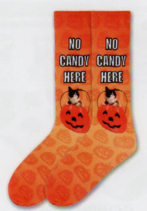 Grumpy Cat Mens No Candy Here Sock starts on an Orange background. All over the Sock are Jack-O-Lanterns in Deep Carrot Orange. Then the Jack-O-Lantern Candy Cauldron that Grumpy Cat is popping out of is Orange Red. Its Handle, Eyes, Nose and Mouth are Black. Below the Cuff in White and Black Print reads, "No Candy Here".