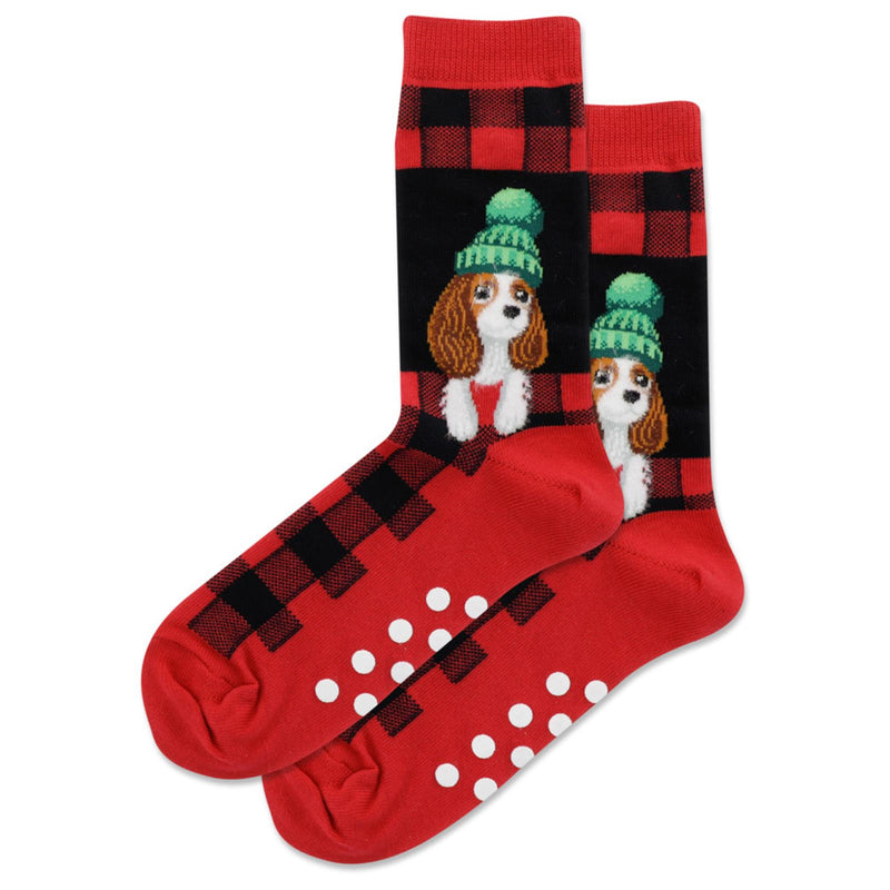 Hot Sox Womens Fuzzy Cavalier King Charles Spaniel Non Skid Socks are Red on the Bottom, and Cuffs. The Rest is Black and Red Plaid. Out of a Black Window pops out the Cavalier King Charles wearing a Green Hat. The Non Skid are White Dots.