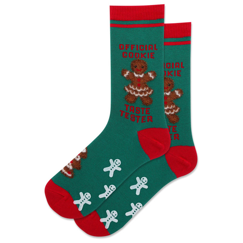 Hot Sox Womens "Official Cookie Taste Tester" Non Skid Socks are Green with Red  Cuffs, Heels, and Toes. Gingerbread Women at Mid-Calf  with Words above and below. The Non-Skid are Gingerbread Cookies. 