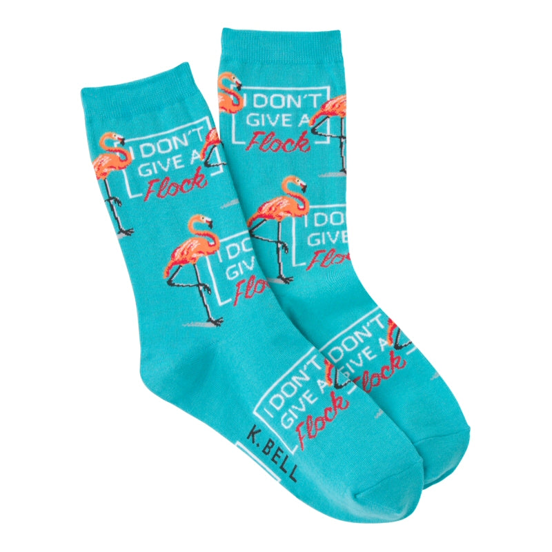K Bell I Don't Give A Flock Sock is coming at you on a background of Turquoise. Flamingos are made with Raspberry, Coquelicot and Coral Pink. They are standing one legged by a Sign Board of White and Raspberry. It says, "I Don't Give a Flock.