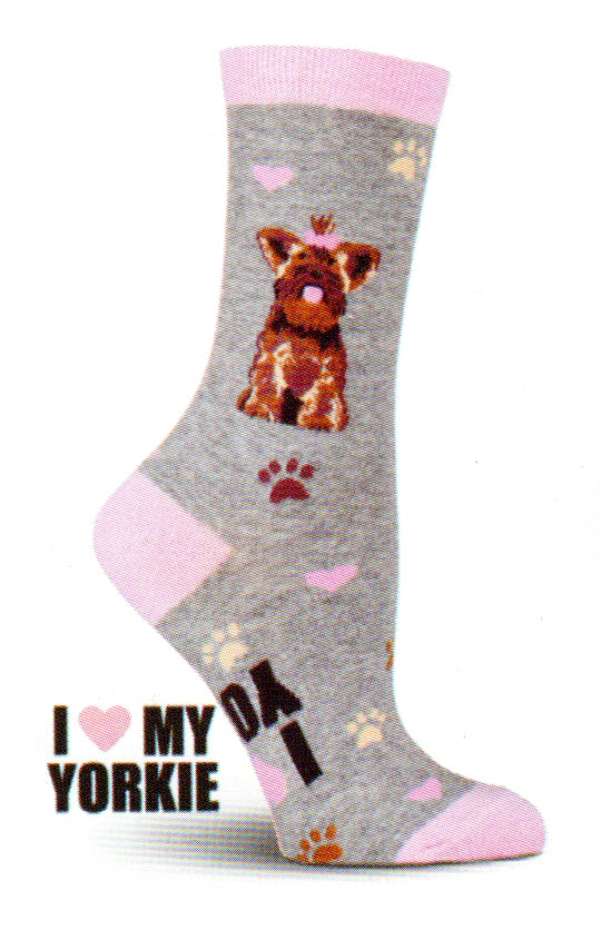 K Bell Yorkie Sock is on a Grey Heather background with Dogwood Pink Cuffs, Heels and Toes. The Yorkie is Brown, Tan, and Black. His Tongue and Bow with hair and the Hearts around him are Spanish Pink. There are Paws in Brown, Chocolate and other colors. 