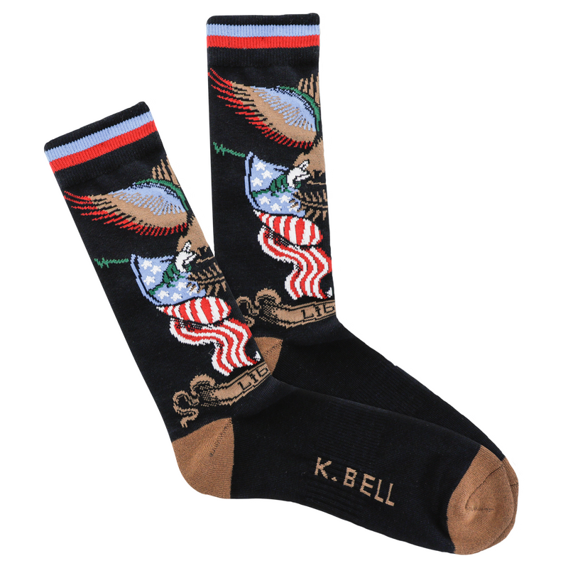 K Bell American Made Mens Tattoo Eagle Over Flag Sock begins on a Black background with Seal Brown Heels and Toes. The Eagle holds the Rod that carries the Flag Bunting. The Eagle is Chocolate, Dark Green, Red, White, Blue and Black. The Flags are Red, White and Blue.  Under the Flags is Bunting in Chocolate with Liberty written on it.