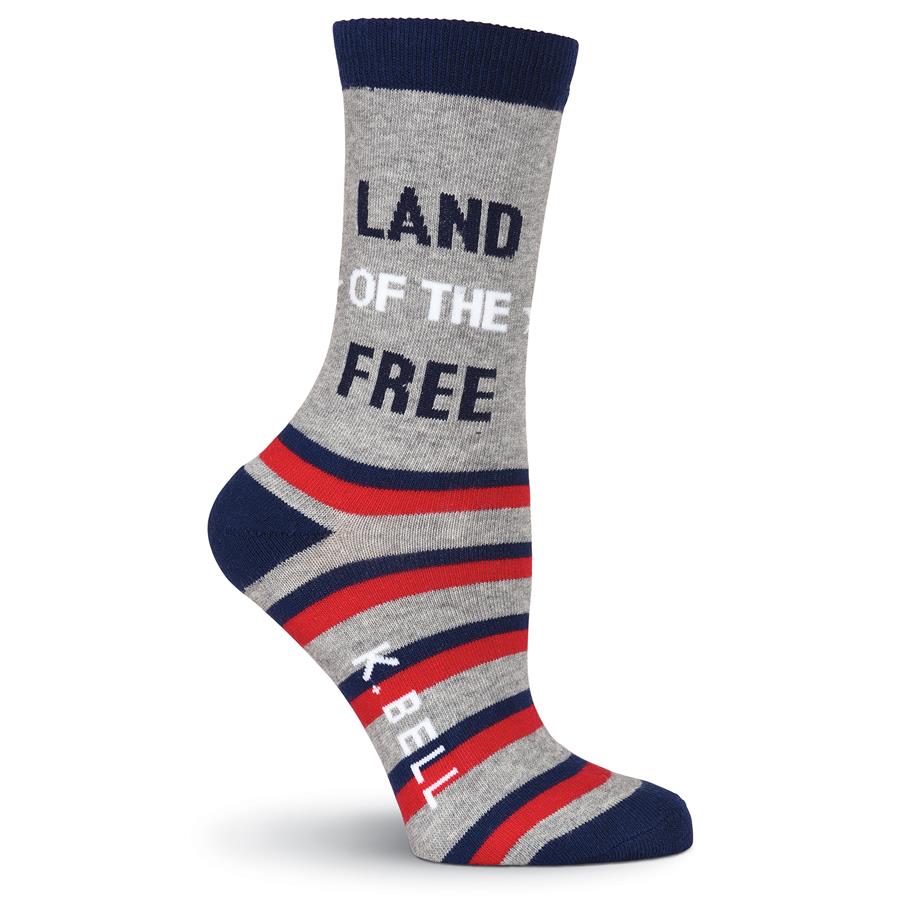K Bell American Made Land of the Free Medium Sock starts on a Light Grey background with Navy Cuff, Heels and Toes. From the Heel to the Toes are Red and Blue Stripes. The the middle of the Grey are the Words on one Sock, "Land of the Free" 