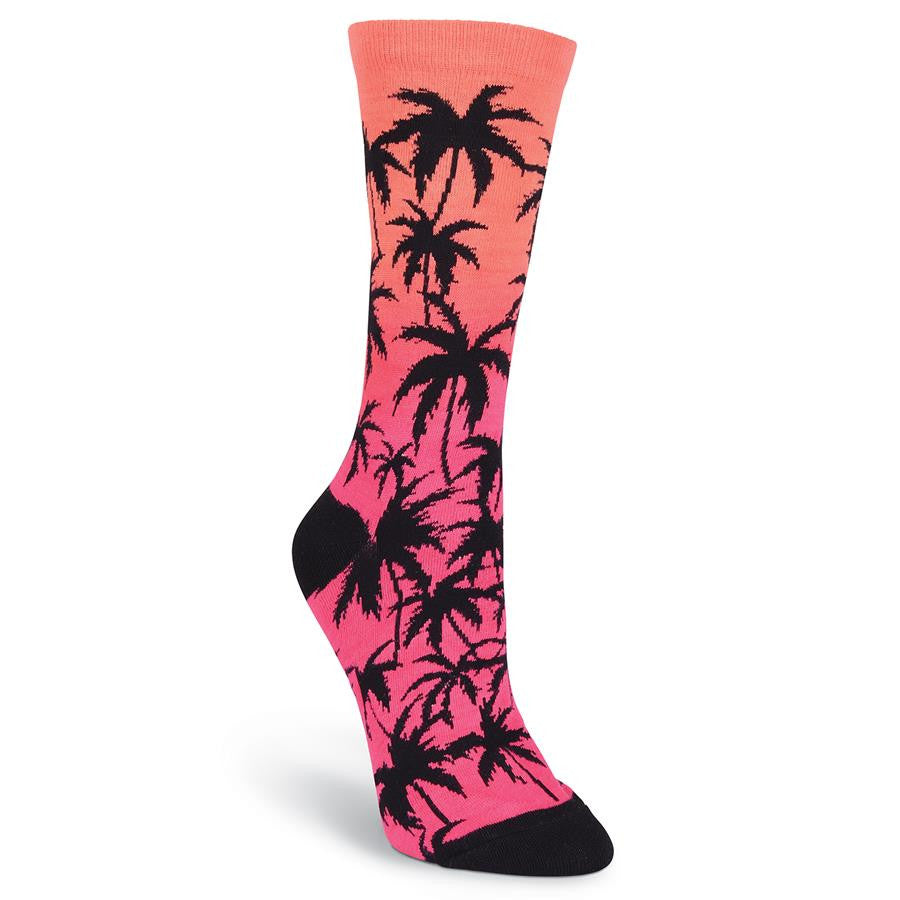 K Bell Womens Palm Crew Sock is background with Pink Sunset. It has Silhouette Palm Trees all over the Sock The Heel and Toes are Black.