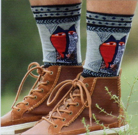 Laurel Burch Mens Native Cat Socks is looking at you like a Native Mask. One Side is all Red with Eyes and some Black. The side of the Cat is White with Black designs and some Red.