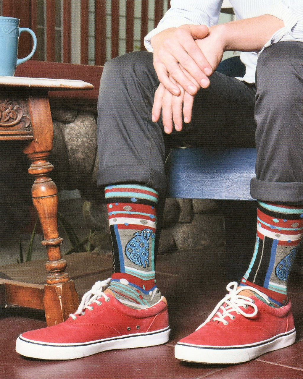 A Model is wearing Mens Laurel Burch Matisse Dog Sock is a Portrait of a Dog in Blues and Greys. In a unique style to favor the Painter Matisse. The socks look great with the Red shoes and Grey pants!