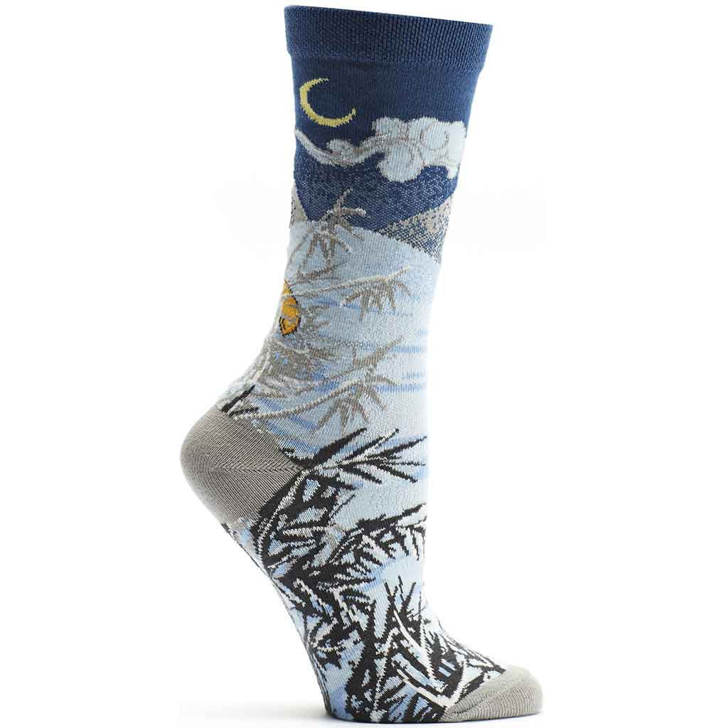 Ozone 4 Seasons Winter Sock starts with a Navy background at the Cuff and below with a Yellow Crescent Moon and Clouds. The Mountain is Snow covered and goes to the bottom where you find a fox hunting for food in snow of white and blues with foliage in Black and Greys.