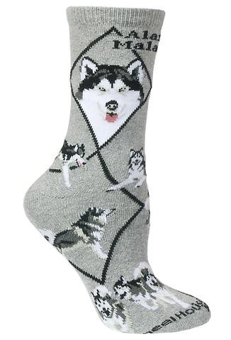 Wheel House Designs Alaskan Malamute Sock starts on a Grey background with Black Diamonds all over. Below the Cuff reads in Bold Black print "Alaskan Malamute" on the center of the Sock. Below on each side are Profiles, one Frontal and one Profile. Next are the Poses which are Walking, Laying Down, Running in a Pack, a Stance and Sitting.