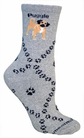 The Puggle Sock starts on a Grey background with the word Puggle in Black at the Top. The cut Puggle is on both sides in Fawn and Cream with Black. The Diamonds are made with Black Dog Paw Prints with Larger ones in the middle.