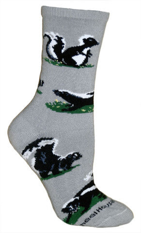 Wheel House Designs Skunk Sock starts on a Grey background. The Skunk has three poses in Black, White and Greys. Also on the sock are Green patches of Grass.